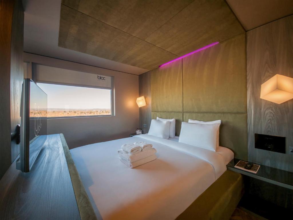 A compact fitted hotel room with a built-in bed, wall storage and a shower unit.