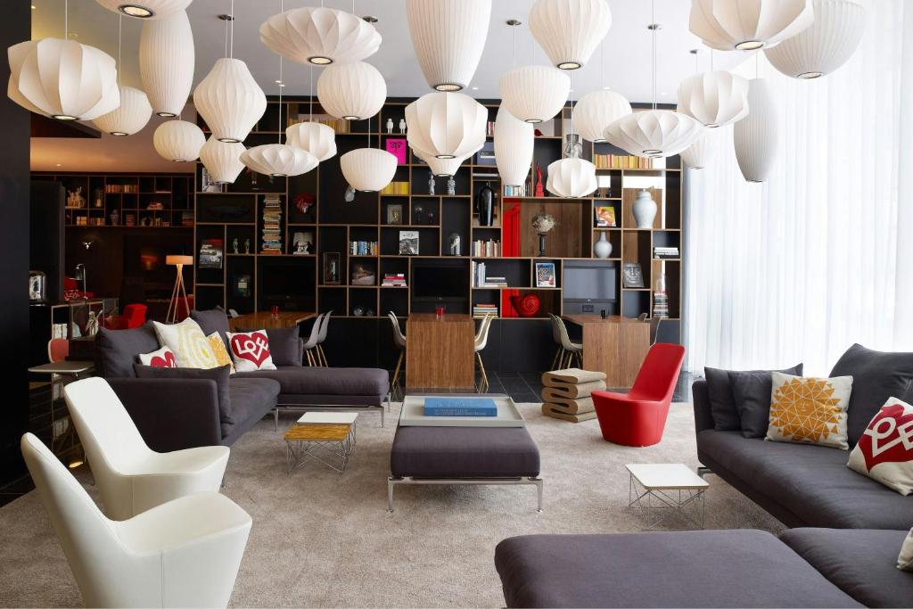 A long open hotel ground floor with mixed seating, work tables and a counter at one end.